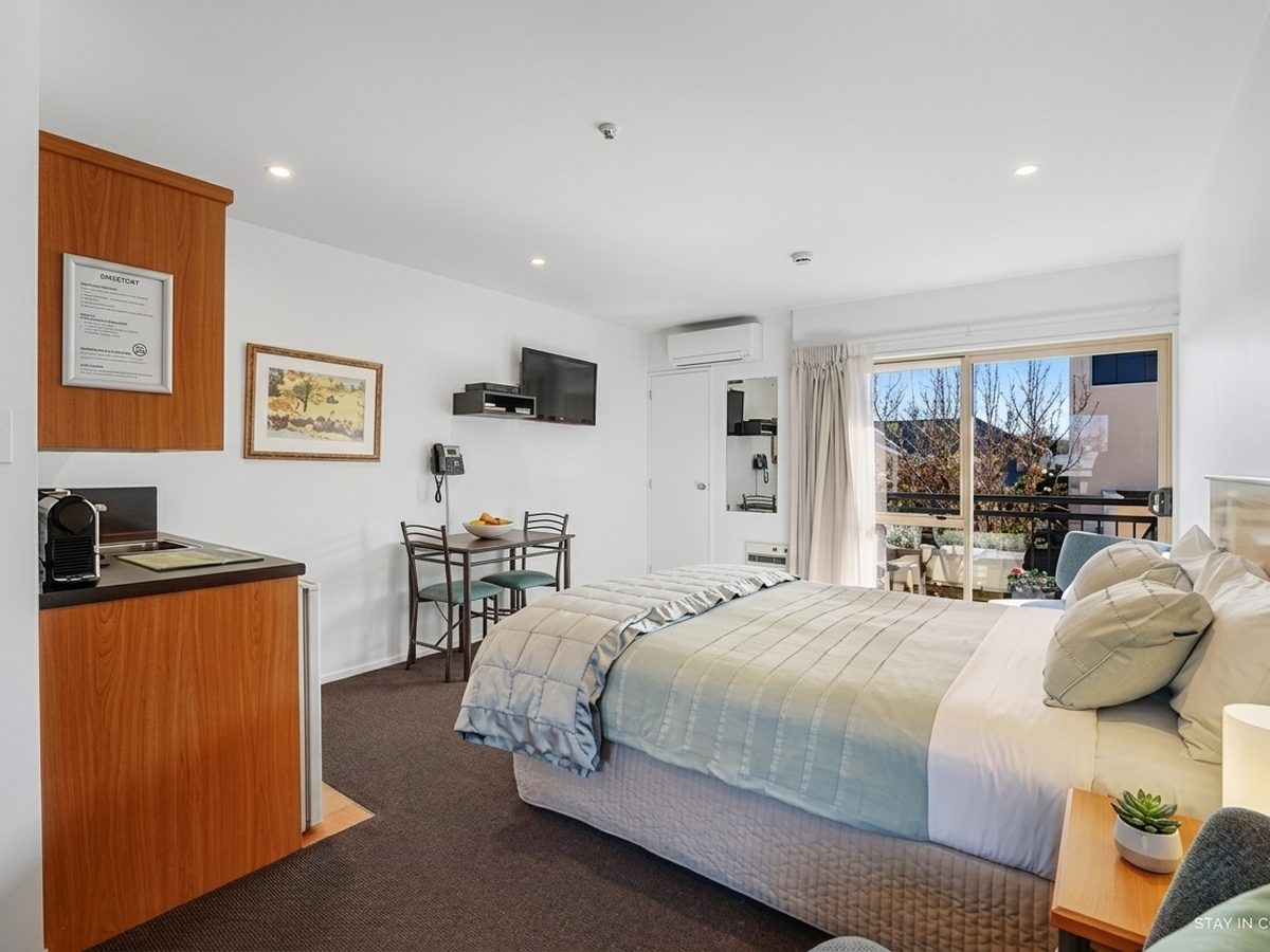 Deluxe Spa Suite with Balcony interior — king bed, spa bath and private balcony overlooking Riccarton